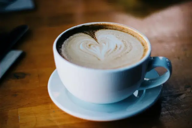 capuchino con dibujo de corazón en taza azul