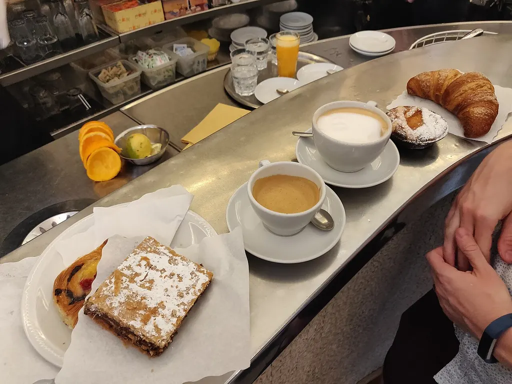 cafés, un cruasán, bollos y zumo de naranja sobre la barra